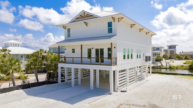 view of front facade featuring fence, board and batten siding, metal roof, driveway, and a carport