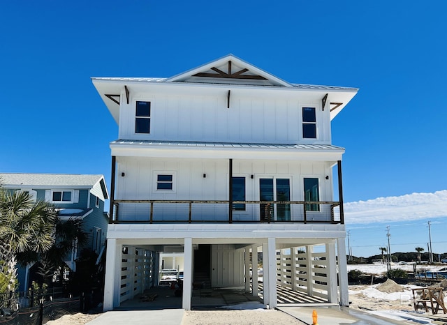 raised beach house featuring board and batten siding, a standing seam roof, metal roof, and a carport