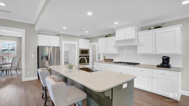 kitchen with recessed lighting, a sink, ornamental molding, and appliances with stainless steel finishes