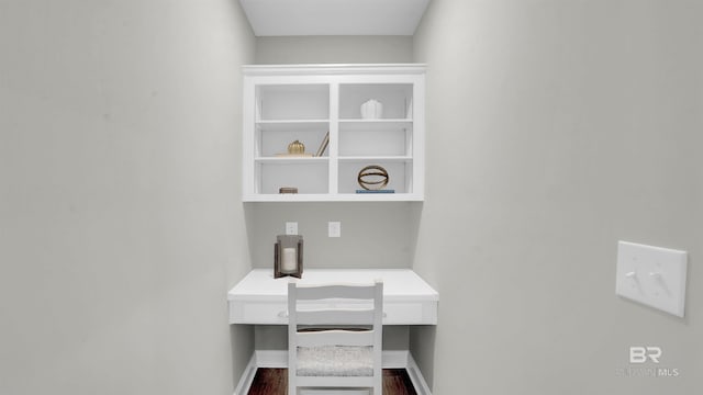 office area with built in desk, baseboards, and dark wood finished floors