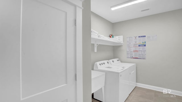 laundry area featuring separate washer and dryer, baseboards, light tile patterned floors, visible vents, and laundry area
