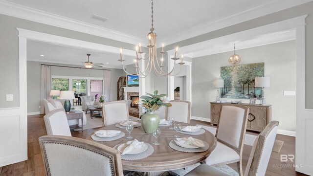 dining room with ornamental molding, wood finished floors, and ceiling fan with notable chandelier