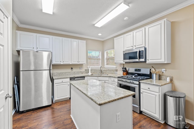 kitchen featuring light stone counters, a center island, stainless steel appliances, white cabinets, and sink