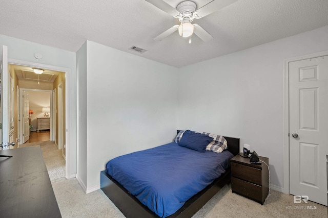 carpeted bedroom featuring ceiling fan and a textured ceiling