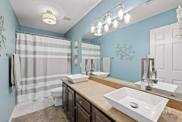 bathroom featuring toilet, a textured ceiling, curtained shower, and vanity