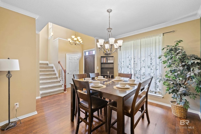 dining room featuring hardwood / wood-style flooring, a textured ceiling, a notable chandelier, and ornamental molding