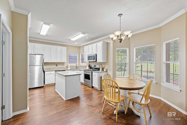 kitchen featuring hanging light fixtures, stainless steel appliances, a kitchen island, an inviting chandelier, and white cabinetry