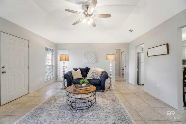 living room with ceiling fan, light tile patterned floors, and a textured ceiling