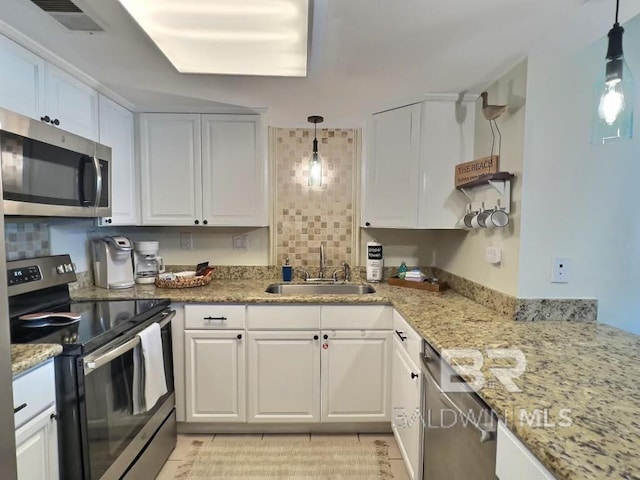 kitchen with sink, white cabinets, decorative backsplash, stainless steel appliances, and decorative light fixtures