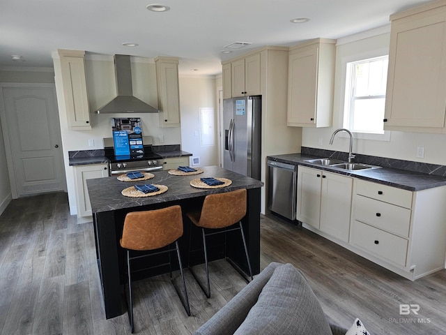 kitchen with sink, a center island, hardwood / wood-style flooring, wall chimney exhaust hood, and stainless steel appliances