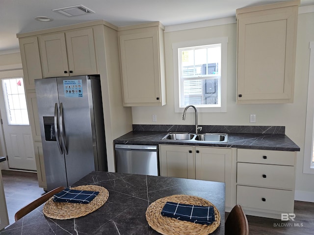 kitchen with appliances with stainless steel finishes, cream cabinets, dark hardwood / wood-style flooring, and sink