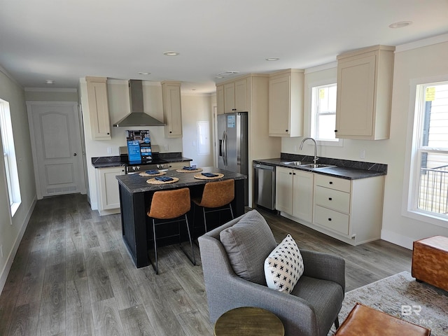 kitchen featuring light wood-type flooring, a wealth of natural light, sink, and wall chimney range hood