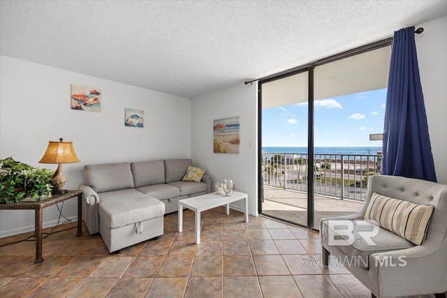 living room featuring floor to ceiling windows, a water view, a healthy amount of sunlight, and a textured ceiling