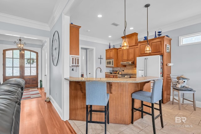 kitchen featuring a peninsula, light stone counters, a breakfast bar, french doors, and appliances with stainless steel finishes