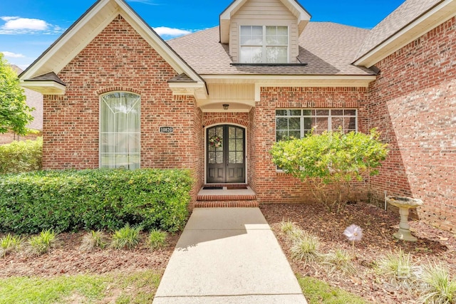 doorway to property with brick siding, roof with shingles, and french doors