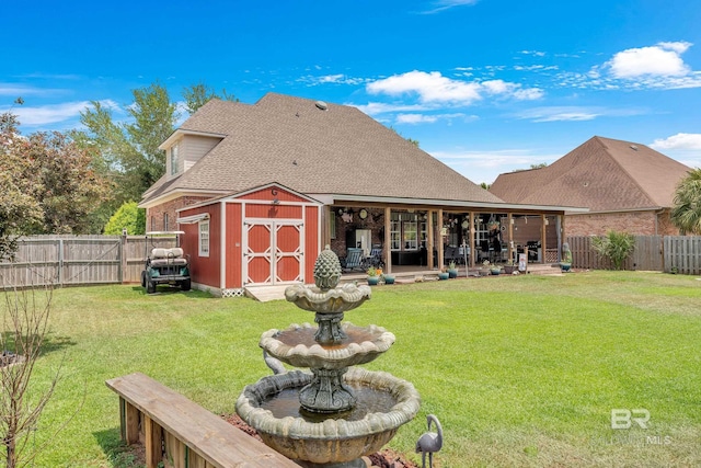 rear view of property featuring a fenced backyard, a storage unit, a patio, and a yard