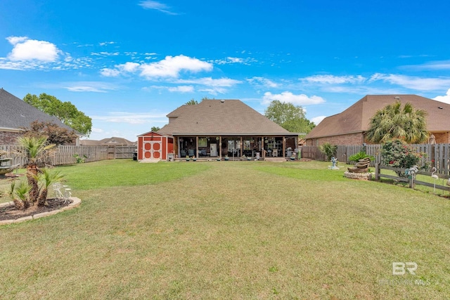 rear view of house with a fenced backyard, a lawn, and a shed