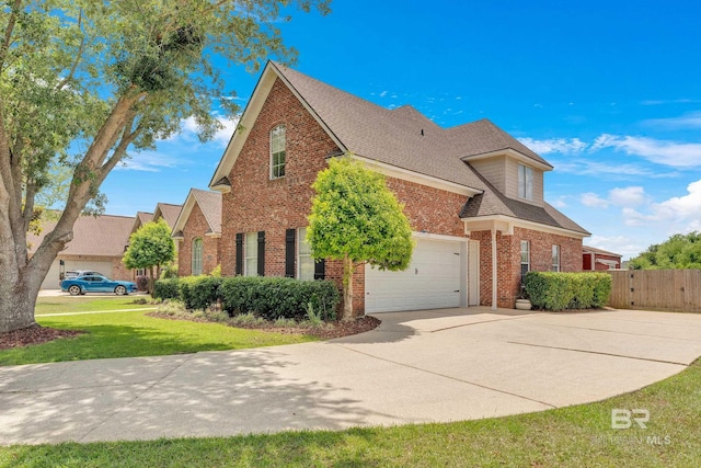 view of front of home featuring roof with shingles, brick siding, fence, a front lawn, and concrete driveway