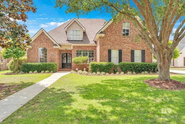 traditional home featuring brick siding, roof with shingles, and a front lawn
