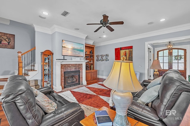 living room with ceiling fan, a fireplace, stairway, ornamental molding, and recessed lighting