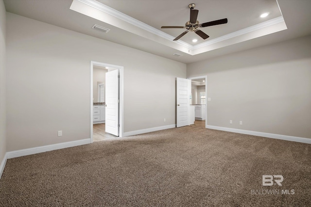 carpeted spare room featuring ornamental molding, a tray ceiling, and ceiling fan