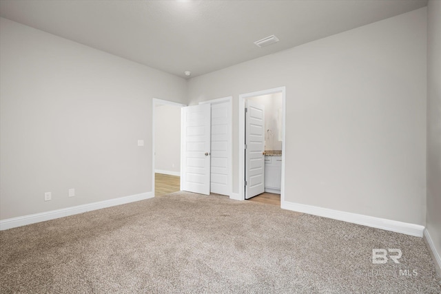 unfurnished bedroom featuring connected bathroom and light colored carpet