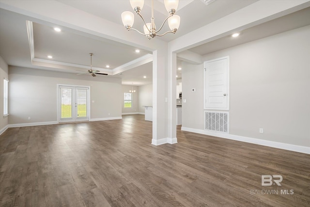 interior space featuring ceiling fan with notable chandelier, crown molding, dark wood-type flooring, and a tray ceiling