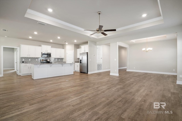 kitchen with ceiling fan with notable chandelier, appliances with stainless steel finishes, a tray ceiling, and white cabinets