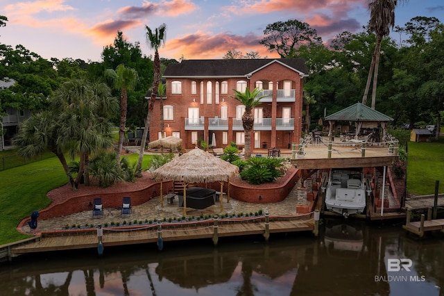 rear view of property with a gazebo, a balcony, a patio, a water view, and boat lift