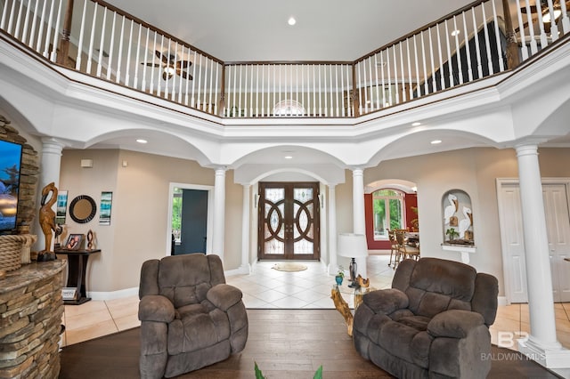 living room featuring decorative columns, a towering ceiling, recessed lighting, tile patterned floors, and french doors