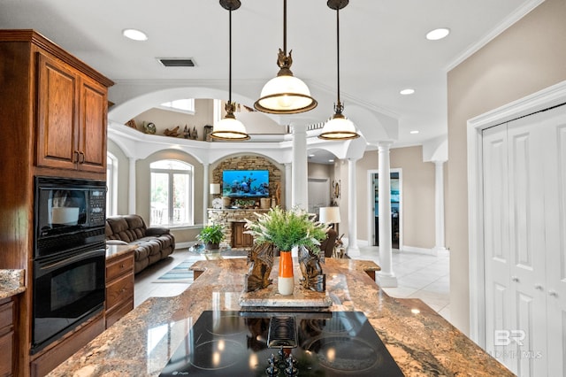 kitchen with decorative columns, black appliances, open floor plan, stone counters, and ornamental molding