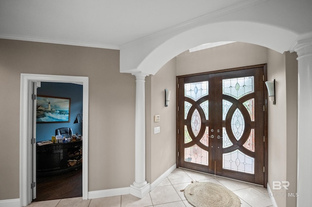 foyer entrance featuring ornate columns, arched walkways, light tile patterned floors, baseboards, and ornamental molding