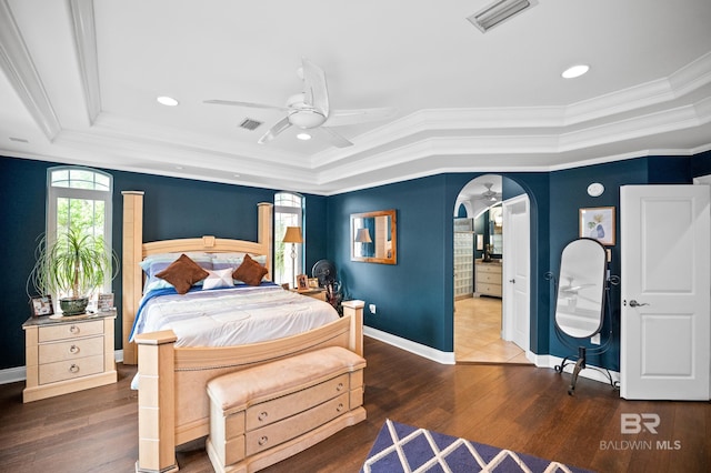 bedroom with a raised ceiling, multiple windows, ornamental molding, wood finished floors, and recessed lighting