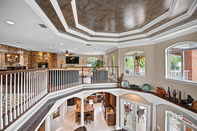 interior space with a raised ceiling, ceiling fan, ornamental molding, a fireplace, and recessed lighting