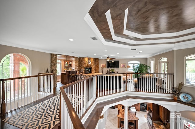 hall featuring a tray ceiling, crown molding, recessed lighting, and an upstairs landing
