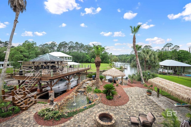 dock featuring a gazebo, view of wooded area, a fire pit, and a patio area