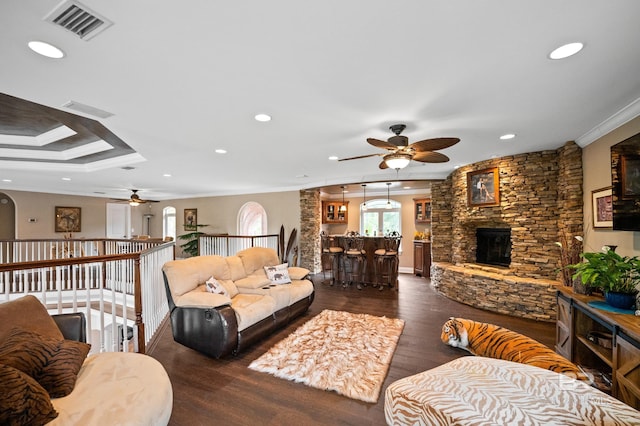 living area featuring ceiling fan, dark wood-style floors, crown molding, recessed lighting, and a stone fireplace