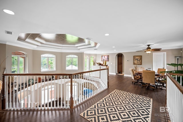 hall featuring arched walkways, wood finished floors, ornamental molding, baseboards, and an upstairs landing
