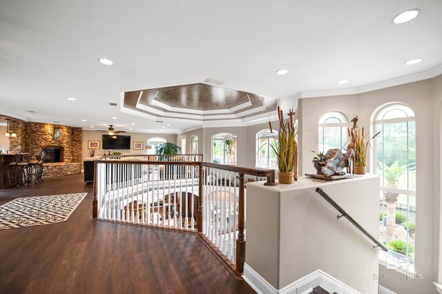 corridor featuring an upstairs landing, wood finished floors, a raised ceiling, crown molding, and recessed lighting