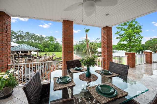 view of patio with ceiling fan, a gazebo, and view of wooded area