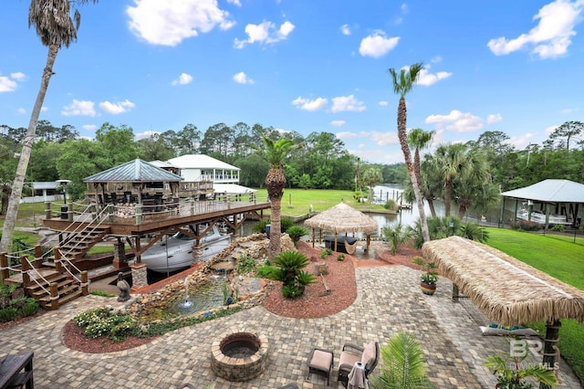 view of grassy yard featuring a gazebo, a fire pit, view of wooded area, and a patio