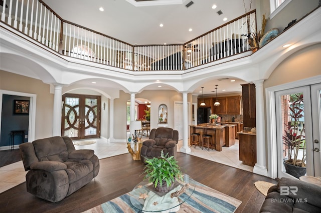 living area featuring decorative columns, arched walkways, a high ceiling, recessed lighting, and french doors
