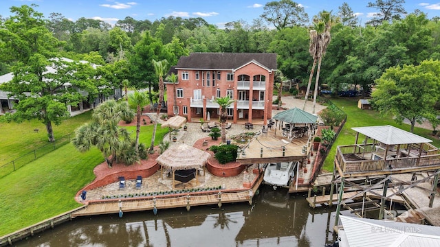back of property featuring a gazebo, a deck with water view, a balcony, and view of wooded area