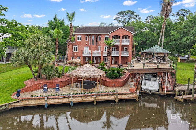 dock area featuring a gazebo, view of wooded area, a balcony, a patio, and a deck with water view