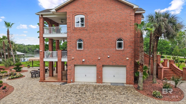 view of side of property featuring a balcony, decorative driveway, a garage, and brick siding
