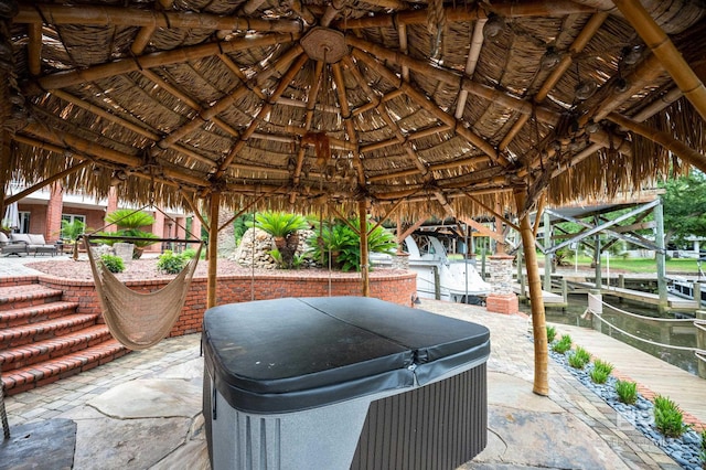 view of patio / terrace with a gazebo, a hot tub, and a boat dock
