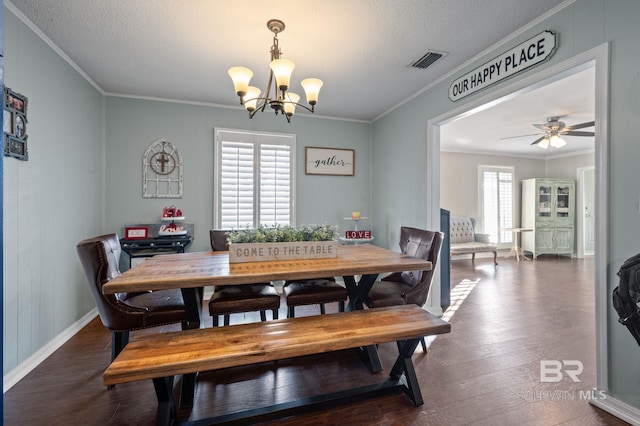 dining space with ceiling fan with notable chandelier, dark wood-type flooring, ornamental molding, and a textured ceiling