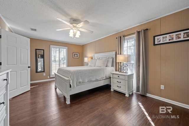 bedroom featuring multiple windows, dark wood-type flooring, ceiling fan, and wood walls