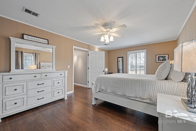 bedroom with crown molding, a textured ceiling, dark hardwood / wood-style floors, and ceiling fan