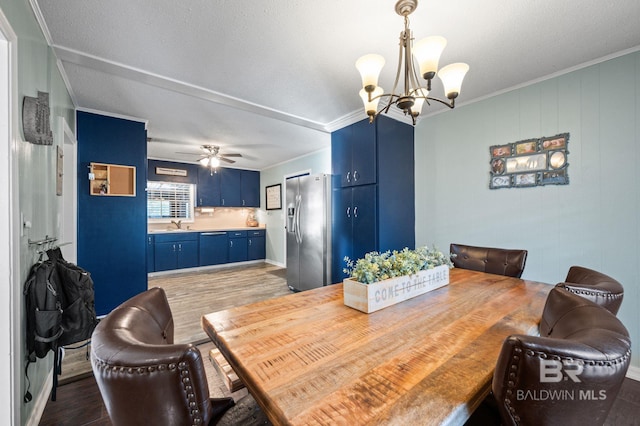 dining space with crown molding, sink, ceiling fan with notable chandelier, and hardwood / wood-style floors